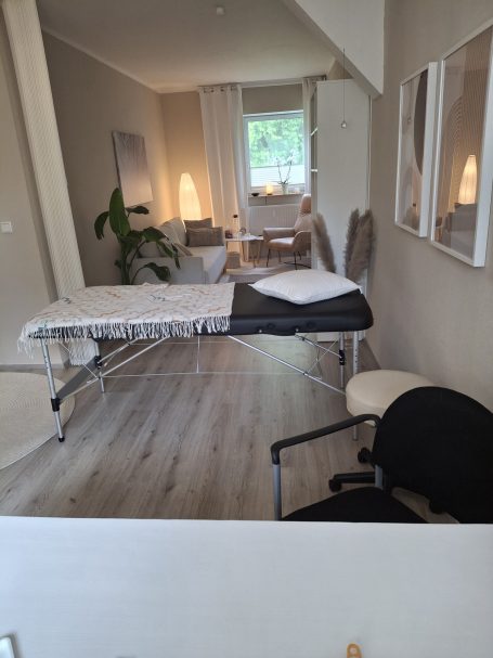 Behandlungsraum mit Behandlungstisch, Stuhl und entspannender Atmosphäre.